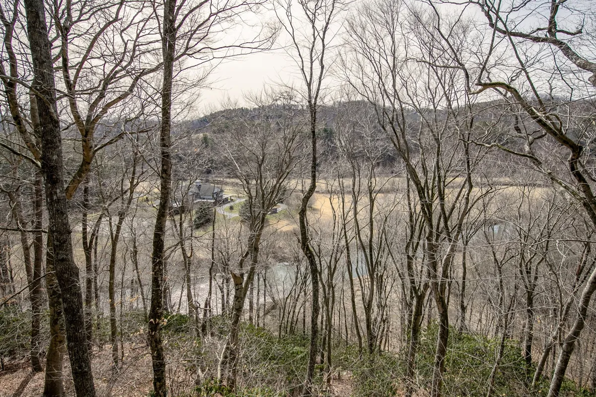 This scenic view captures a river meandering through bare trees and open fields with distant hills on the horizon. The peaceful atmosphere suggests opportunities for hiking, fishing, and exploring the natural surroundings mentioned in the section.